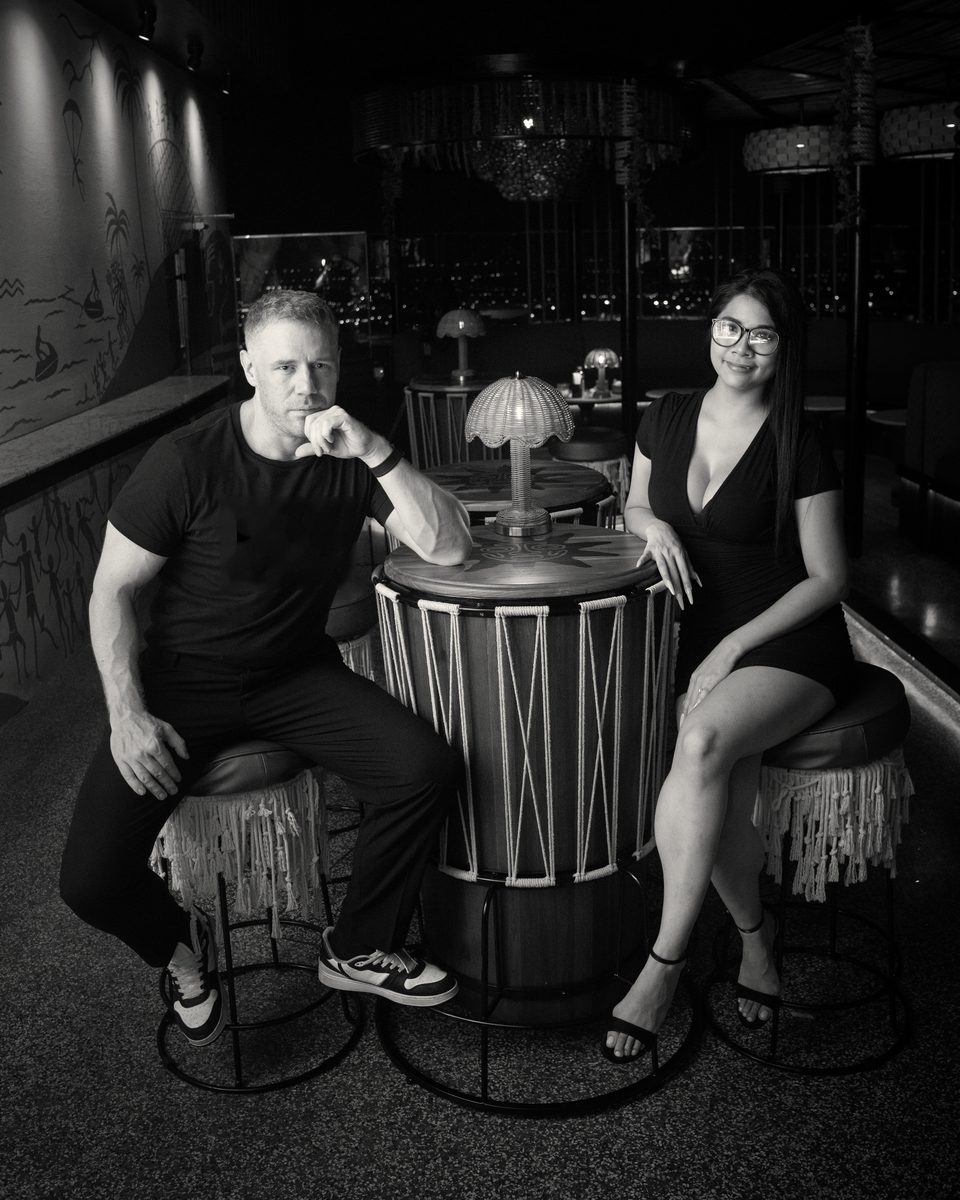 Tim and Paemi seated at a table in a lounge in Pattaya, facing the camera